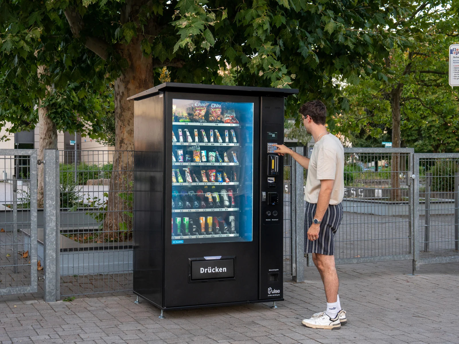 Kunde kauft am Pulse PV1100 Snackautomaten an einem Außenstandort